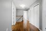 Hallway featuring wood-finish flooring, white paneled doors, and a wood railing with white spindles