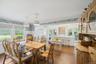 Dining room with dark wood-type flooring, a chandelier, ornamental molding, wallpapered walls, and wainscoting