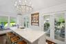 Kitchen with french doors, plenty of natural light, light stone countertops, a center island with sink, and vaulted ceiling