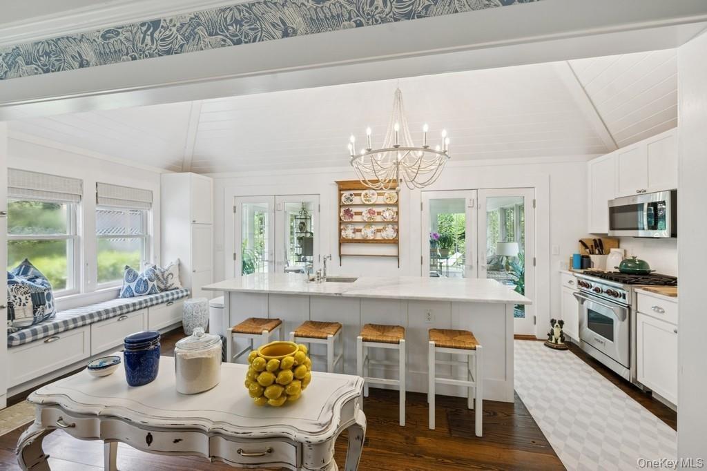 Kitchen featuring appliances with stainless steel finishes, plenty of natural light, dark wood finished floors, a breakfast bar area, and wooden ceili