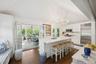 Kitchen featuring stainless steel appliances, a chandelier, dark wood-style floors, white cabinetry, and an island with sink