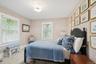 Bedroom with multiple windows, wallpapered walls, and wood finished floors