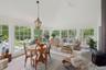 Sunroom / solarium featuring vaulted ceiling, plenty of natural light, a wood stove, and stone tile flooring