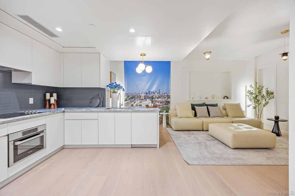 Kitchen with modern cabinets, stainless steel oven, white cabinets, and hanging light fixtures