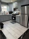 Kitchen with gray cabinets, fridge, stainless steel stove, decorative backsplash, and recessed lighting