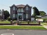 Brick exterior featuring a Juliet balcony with metal railing, arched windows, and full glass entryway with double doors.  Fenced in yard with brick an