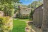 Spacious backyard oasis featuring a manicured lawn, mature tree canopy providing natural shade, and a detached storage structure