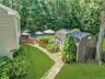 Expansive backyard oasis featuring a professionally manicured lawn, mature tree canopy, stone-paved pathway, in-ground swimming pool with wooden deck,