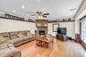 Living room featuring hardwood flooring, a stone-clad fireplace with mantel, recessed lighting, and a ceiling fan