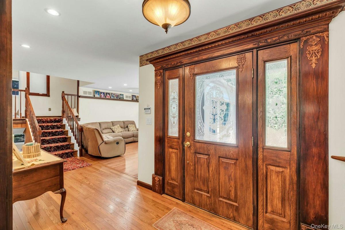 Elegant foyer showcasing ornate wood-paneled double doors with decorative glass inserts and detailed molding