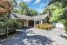 Charming ranch-style home featuring a welcoming brick chimney, composite siding exterior, and asphalt driveway