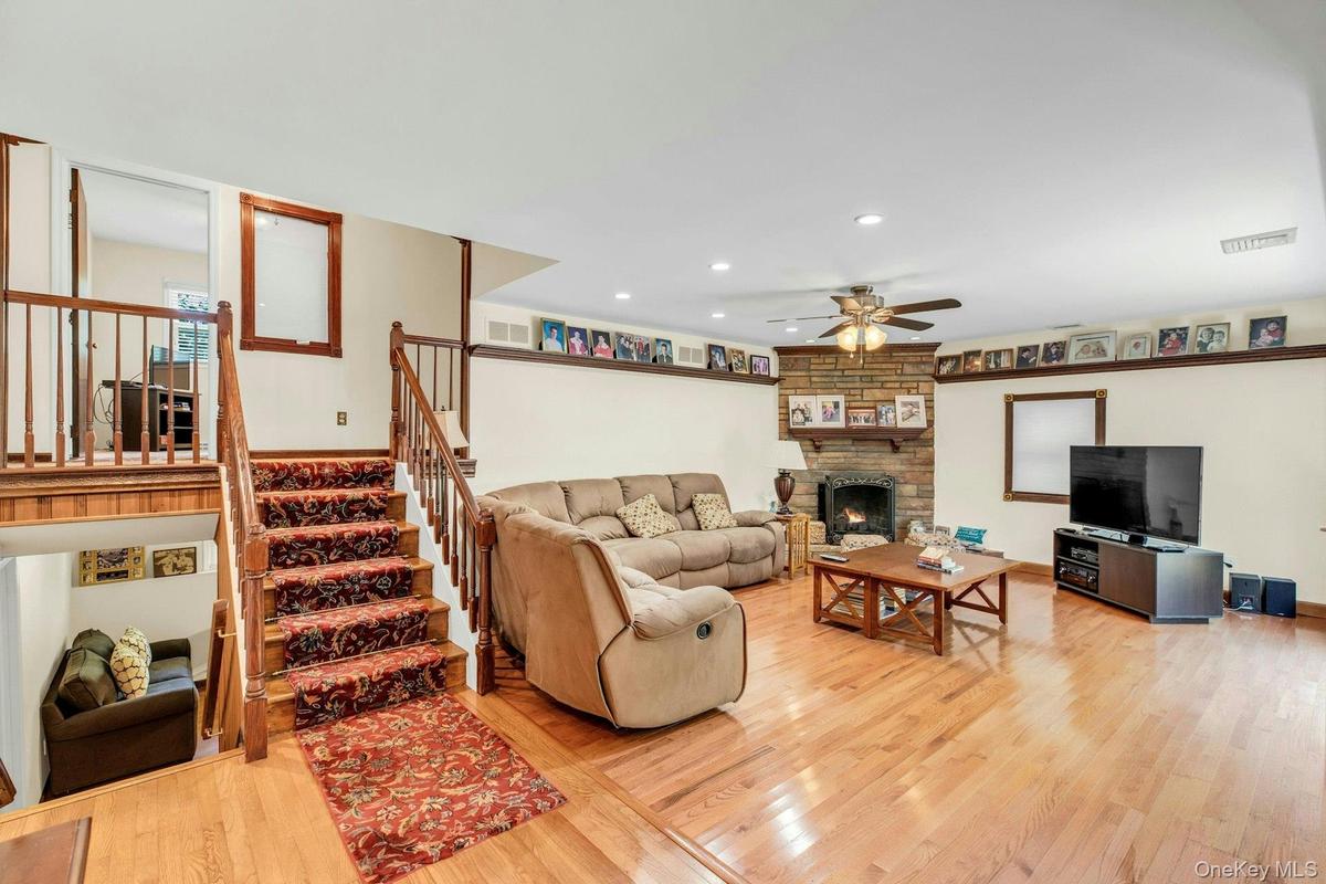 Open-concept living space featuring hardwood flooring, a wood-burning fireplace with surround, and multiple seating areas