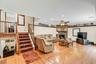 Open-concept living space featuring hardwood flooring, a wood-burning fireplace with surround, and multiple seating areas