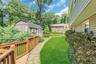 Expansive backyard retreat featuring a manicured lawn, mature tree canopy, and stone paver pathway