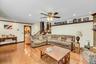 Spacious open-concept living area showcasing hardwood flooring, a neutral upholstered sectional sofa, coffered ceiling with ceiling fan, recessed ligh