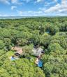 Aerial view showcasing a sprawling wooded estate with mature tree canopy, multiple residential structures, and resort-style amenities including an in-