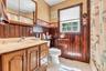 Classic bathroom featuring rich wood cabinetry with multiple drawers and storage, ceramic sink with chrome fixtures, and white ceramic toilet