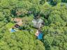 Expansive property featuring two distinct structures surrounded by mature trees
