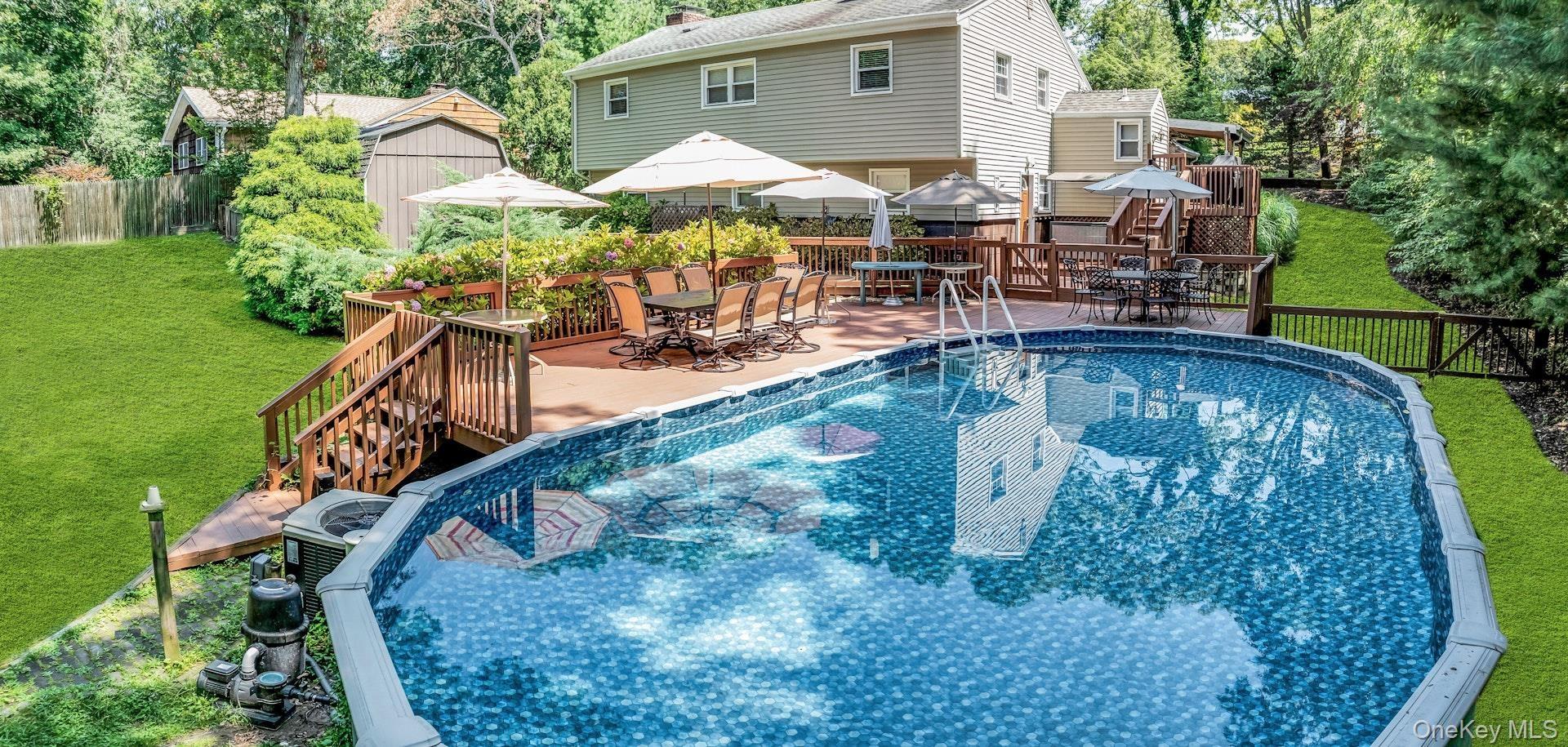 Expansive backyard featuring an above-ground pool, a multi-level wood deck, and surrounding greenery