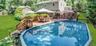 Expansive backyard featuring an above-ground pool, a multi-level wood deck, and surrounding greenery