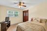Bedroom featuring a ceiling fan with integrated lighting, a window with blinds, baseboard heating, and wood-paneled bifold closet doors
