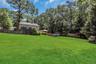 Expansive green lawn with a wooden privacy fence bordering mature trees