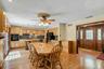 Spacious kitchen and dining area featuring warm wood cabinetry, stainless steel appliances, wood-finish flooring throughout, a ceiling fan with integr