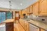 Kitchen featuring light wood cabinetry, a stainless steel dishwasher, a double basin sink, and pendant lighting