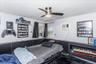 Room featuring a ceiling fan with integrated lighting, white walls, and dark wainscoting
