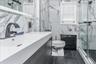 Spa-inspired primary bathroom featuring marble-look wall tile, dark tile flooring, and a floating vanity with an integrated rectangular sink