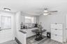 Contemporary kitchen featuring white cabinetry, dark countertops, a stainless steel sink with a gooseneck faucet, and wood-finish flooring