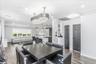 Open-concept interior featuring wood-finish flooring, a contemporary chandelier, recessed lighting, a kitchen island with seating, and dark panel door