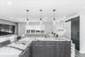Kitchen island featuring a waterfall-edge countertop with prominent veining, wood-finish cabinetry, and three pendant lights