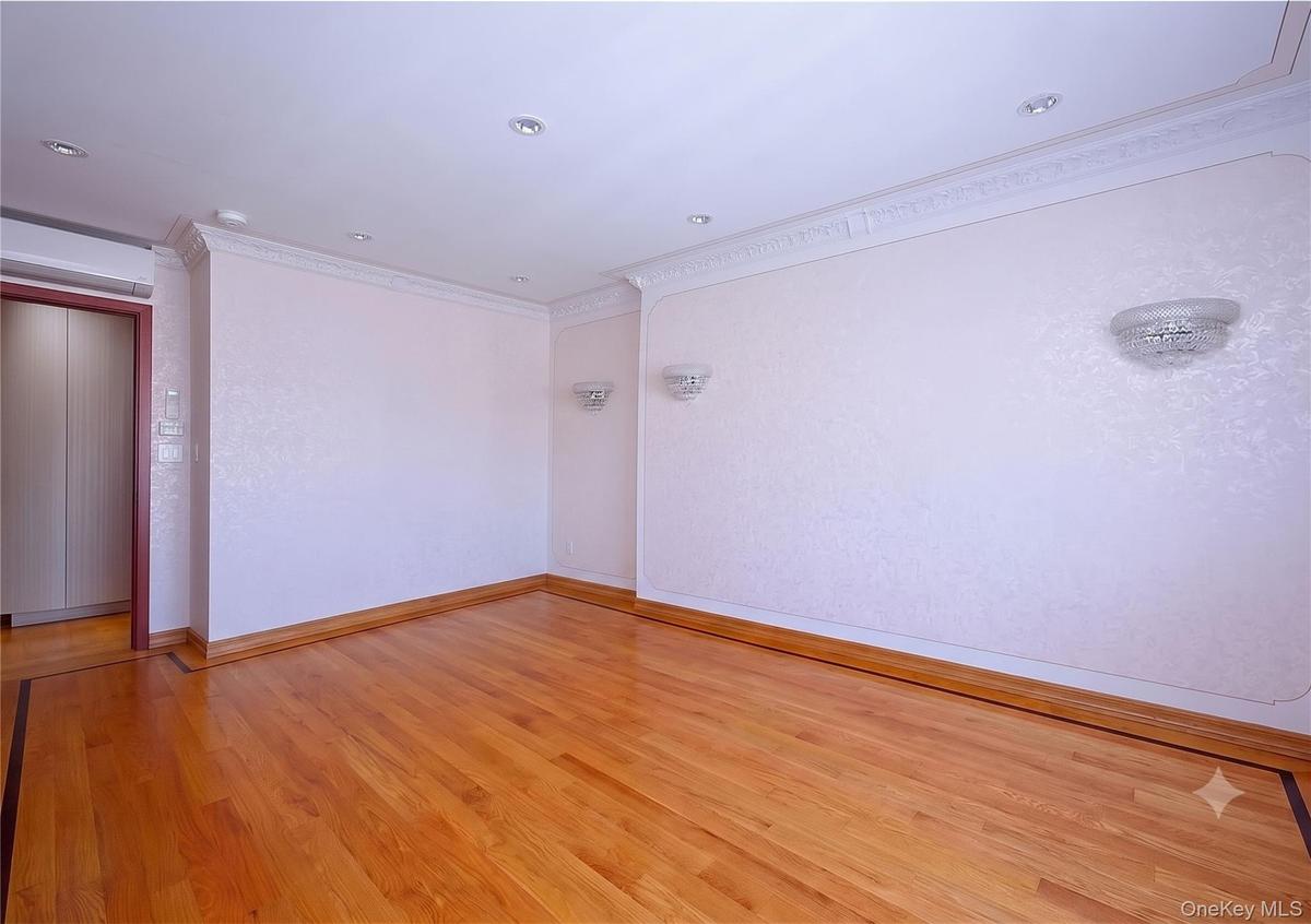 Bright room featuring wood-finish flooring with a decorative border, recessed lighting, and wall sconces