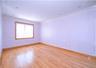 Bright, light-filled room featuring gleaming wood-finish flooring, crisp white wainscoting and wall paneling, recessed ceiling lighting, and a large w