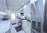 Galley kitchen featuring white cabinetry with brushed nickel hardware, granite countertops, stainless steel appliances, and recessed lighting