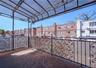 Outdoor patio featuring a clear overhead canopy, decorative metal railings with frosted panels, and brick-patterned paving