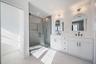 Spa like primary bath featuring a freestanding soaking tub, oversized glass shower, and modern finishes.