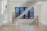 Striking staircase with modern railing and large window wall that brings light into both levels and adds architectural character.