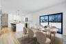 Bright dining space positioned beside kitchen and living room featuring wet bar and large glass sliders, offering great natural light and easy access 