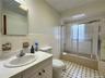 Bathroom featuring tiled shower / bath, vanity, and tile walls