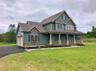 This impressive side view showcases the home’s generous yard, expansive outdoor space, and peaceful wooded surroundings, offering a rare combination o