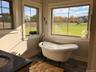 A freestanding soaking tub is perfectly positioned to capture peaceful outdoor views creating a relaxing spa inspired retreat.