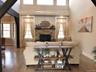 This expansive great room features soaring vaulted ceilings, gleaming red oak hardwood flooring, and abundant natural light.