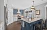Dual tone kitchen with a breakfast bar area, a peninsula, light stone counters, stainless steel appliances, and decorative light fixtures