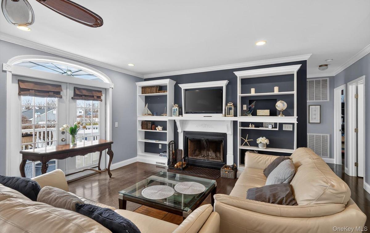 Living room with crown molding, a fireplace with flush hearth, wood finished floors, and recessed lighting