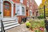 Brick facade row house featuring a paneled wood-finish entry door with leaded glass, an arched transom, and white trim