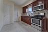 Kitchen featuring stainless steel appliances, rich wood-finish cabinetry, granite countertops, and a mosaic tile backsplash