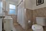 Bathroom featuring floor-to-ceiling tile, a single-pane window, and a built-in toilet