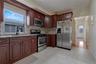 Kitchen featuring wood-finish cabinetry, stainless steel appliances, a multi-tone tile backsplash, and light-toned tile flooring